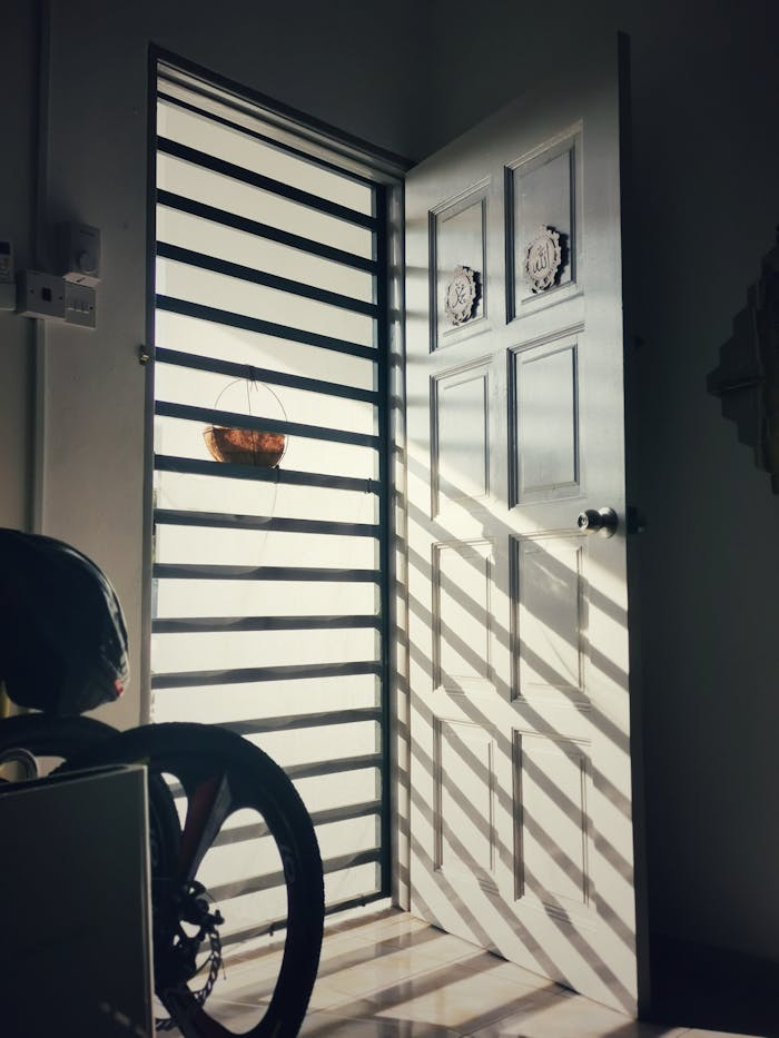 An open door casting dramatic shadows indoors in Klang, Selangor. Sunlight accentuates the room's peaceful atmosphere.